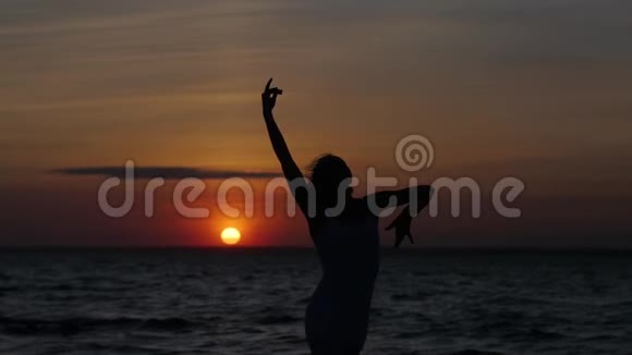 在日落和大海的背景下跳舞的女人的剪影视频的预览图