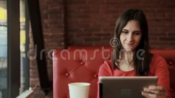 女人用平板电脑触摸屏在咖啡馆喝茶视频的预览图