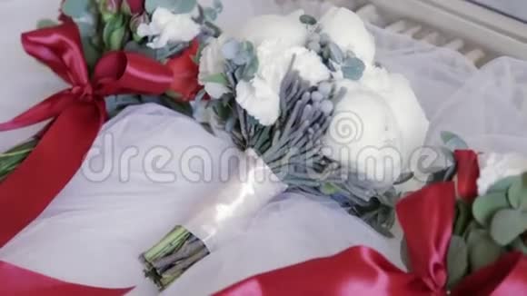 一束美丽的白皮子的婚礼花被另外两束放在白色面纱材料上肖像没有视频的预览图