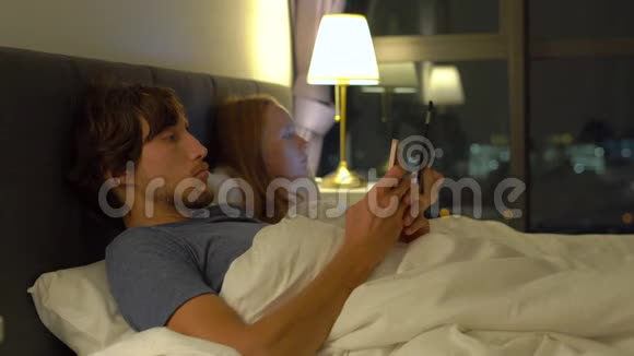 男人和女人躺在床上每个人都有智能手机和平板电脑婚姻和两性关系问题视频的预览图