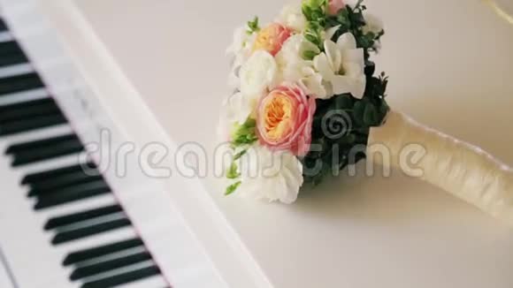 白色钢琴上五颜六色的婚礼花束新娘配饰粉色玫瑰甜湾玉兰周围没有人视频的预览图