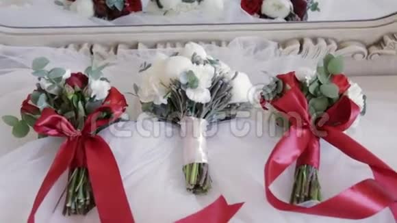 近距离观看白色缎子材料上的婚礼花束为新娘准备的带皮的白玫瑰红玫瑰系视频的预览图