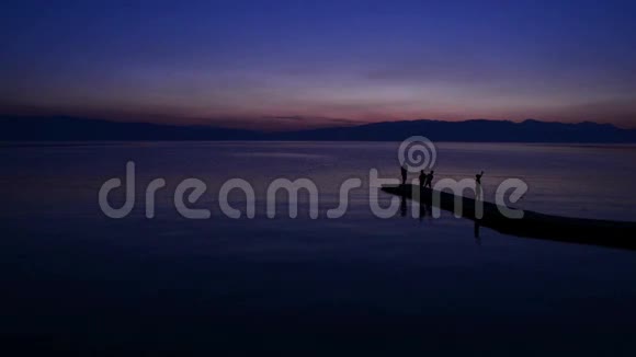 人们在平静的湖面上欣赏日落视频的预览图