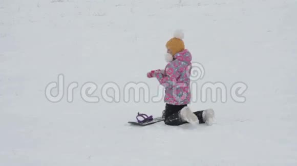 女孩在滑雪板上学习骑山坡视频的预览图