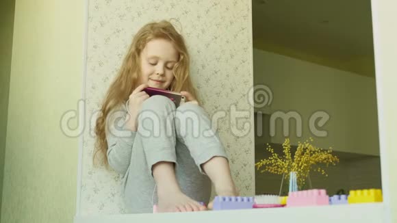 坐在窗户上的小女孩用电话视频的预览图
