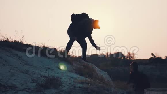 两个徒步旅行在山上互相帮助团队合作情侣徒步旅行互相帮助信任帮助日落视频的预览图