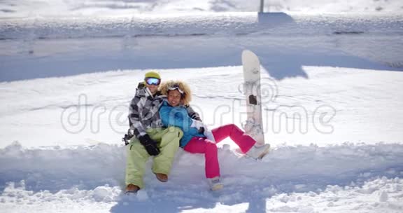 幸福的年轻夫妇坐在厚厚的雪架上视频的预览图