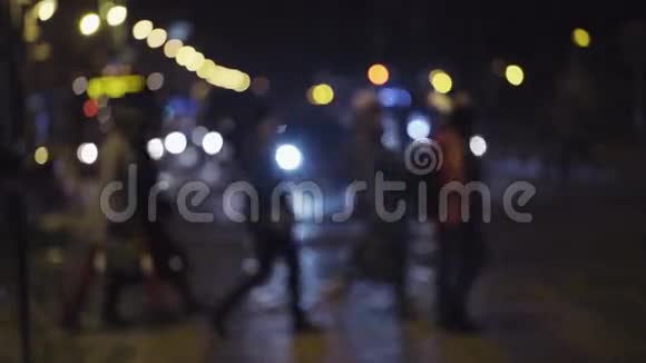 市中心夜间交通的慢镜头行人在人行横道上穿过街道模糊的图像视频的预览图