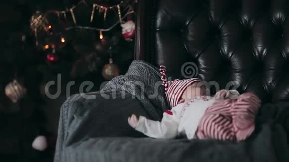 在圣诞树附近的椅子上睡觉的新生儿视频的预览图