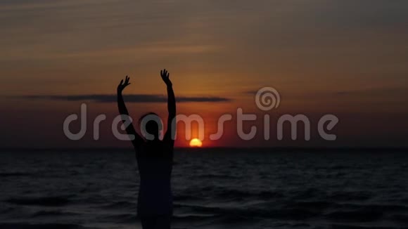 在日落和大海的背景下跳舞的女人的剪影视频的预览图