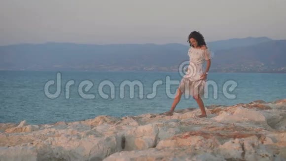 一位穿着裙子走在岩石上的年轻美女视频的预览图