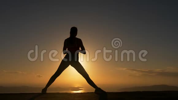 日出时在海边做瑜伽健身运动的女性剪影视频的预览图