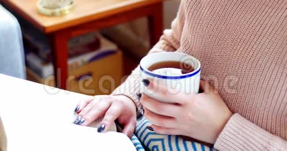 女人在客厅喝咖啡的时候读小说视频的预览图