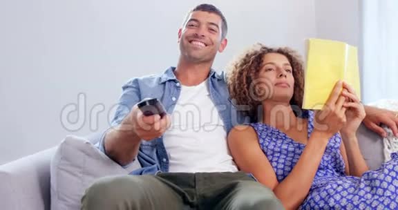 可爱的夫妇看电视和读书视频的预览图