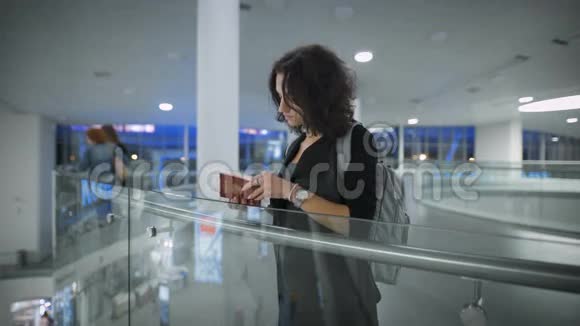 一位年轻漂亮的女士正在机场看她的护照视频的预览图