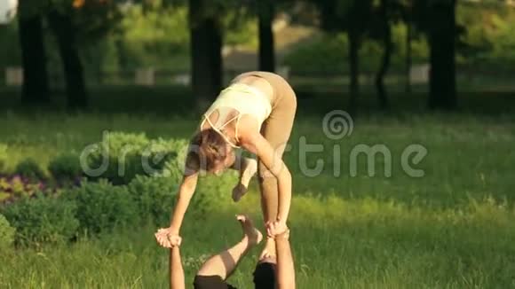 很棒的一对练习杂技瑜伽专业瑜伽教练在城市公园练习两名成功青年视频的预览图