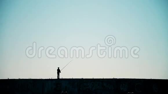 日落时分一名男子从有工业背景的防波堤上钓鱼视频的预览图