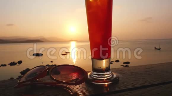 一杯龙舌兰酒日出酒精鸡尾酒站在木桌上旁边是太阳镜和手机视频的预览图