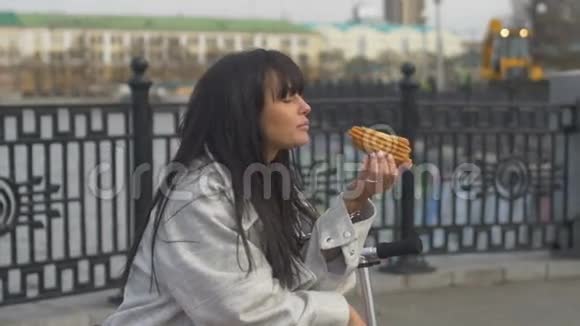 年轻女人在长凳上吃三明治视频的预览图