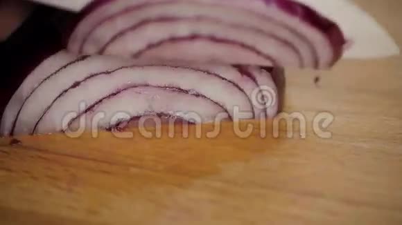 双手紧握锋利的刀在厨房里用浅色的面切下鲜红色的洋葱视频的预览图