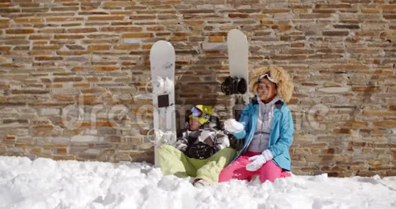 坐在堆雪堆里的滑雪朋友视频的预览图