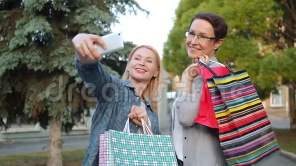 女人在户外用智能手机拍照摆着购物袋视频的预览图
