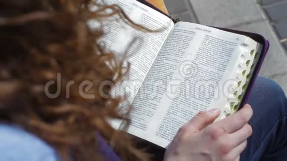 坐在公园长凳上看圣经书的女人视频的预览图