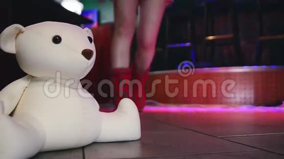 模特穿着柔软的拖鞋在夜总会的地板上行走毛绒熊玩具视频的预览图