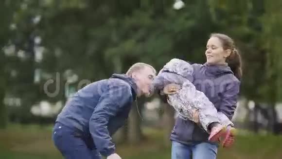 幸福的家庭爸爸妈妈和小女孩在秋天公园散步在草地上玩耍视频的预览图