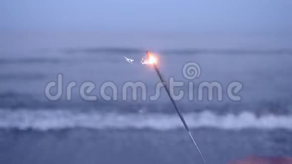 在大海的背景下手中燃烧着孟加拉火视频的预览图
