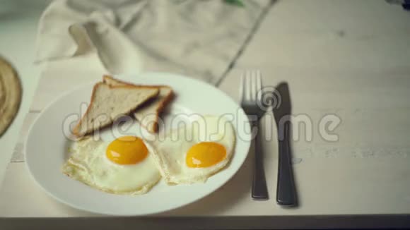 女人的手把盘子放在桌子旁边盘子里放着煎蛋视频的预览图
