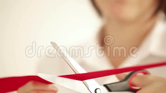 女人用剪刀剪红带子视频的预览图