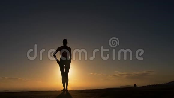 日出时在海边做瑜伽健身运动的女性剪影视频的预览图