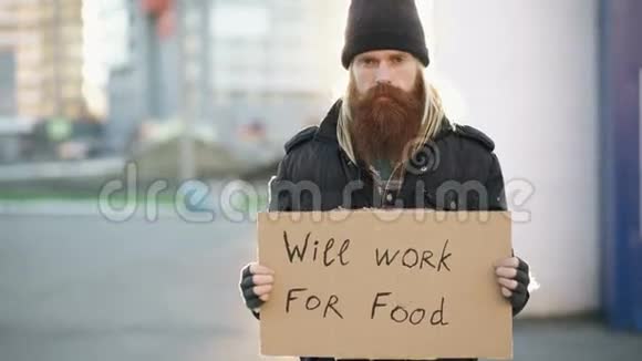 无家可归的年轻人拿着纸板看相机想在街上买食物看相机的画像视频的预览图