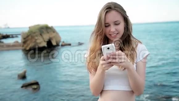 混合种族美丽微笑的年轻女子手持智能手机在夏威夷海滩日落视频的预览图