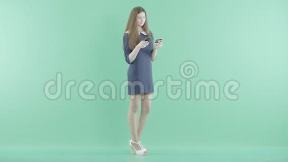 一个年轻的女孩拿着卡片和电话站着视频的预览图