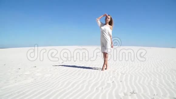 穿着白色裙子站在沙漠里的漂亮女孩视频的预览图
