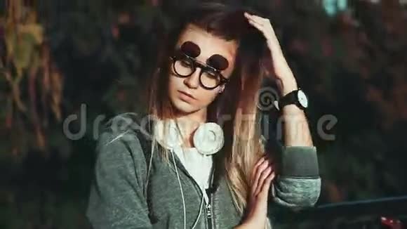 在城市公园里戴着耳机和时髦眼镜的女孩视频的预览图