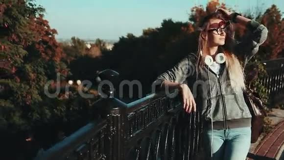 在城市公园里戴着耳机和时髦眼镜的女孩视频的预览图