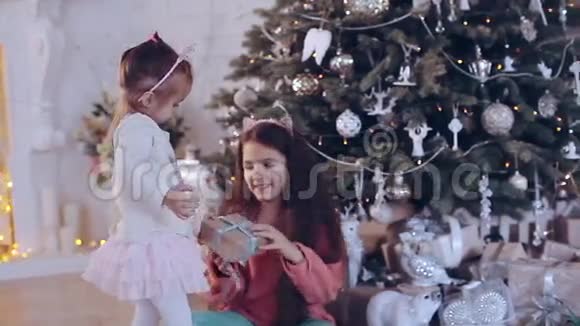 两个女孩在圣诞树旁带礼物视频的预览图