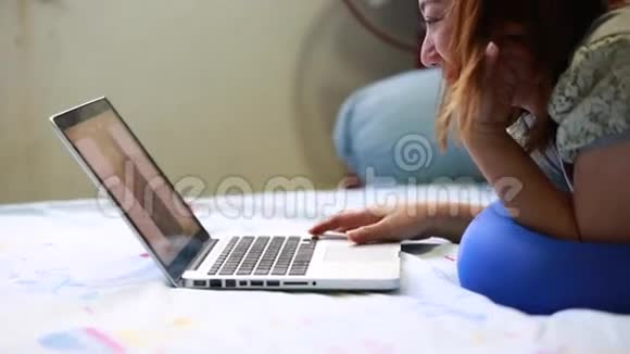 一个轻松的女人在家里用笔记本电脑的肖像亚洲女孩视频的预览图