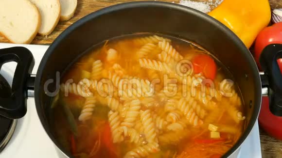 蔬菜或小汤与意大利面煮在金属平底锅上的炉子视频的预览图