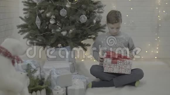 小快乐兴奋的男孩打开圣诞礼物盒装饰新年树节日气氛室视频的预览图