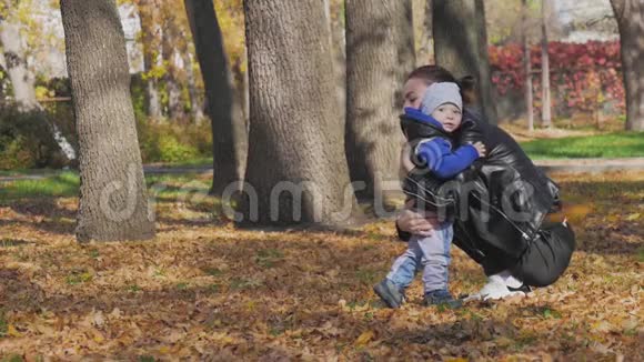 妈妈在一个秋天的公园里围着一个小儿子转秋天公园的幸福家庭慢生活中的幸福家庭视频的预览图