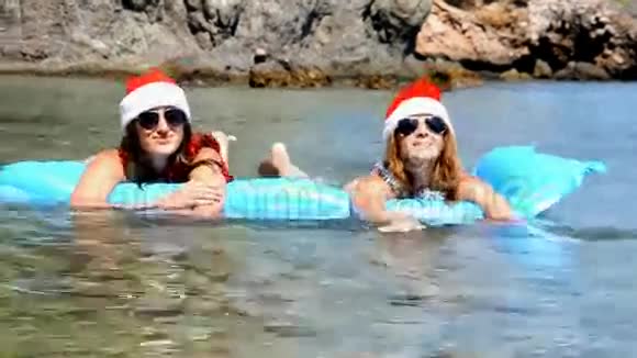 美丽的年轻女子戴着圣诞帽在海里游泳视频的预览图