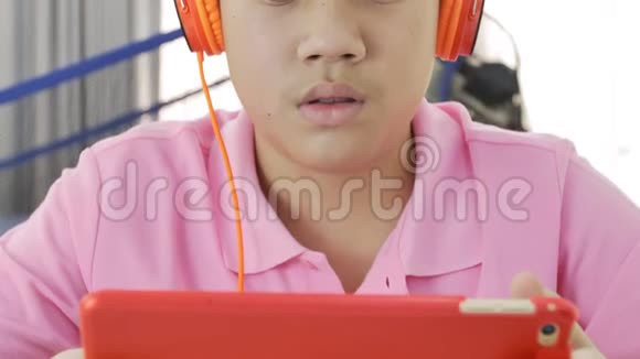 快乐的亚洲男孩玩平板电脑男孩吃一块苹果看平板电脑视频的预览图