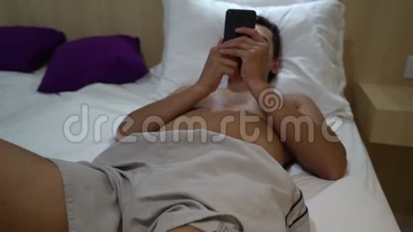 男人在床上放松在智能手机上阅读近距离稳定射击休闲活动视频的预览图
