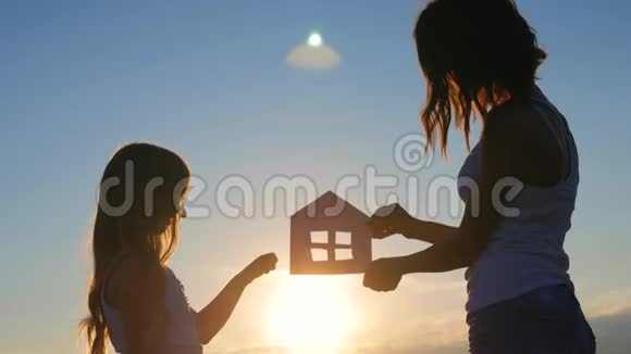 剪影幸福的母女和梦想的房子纸房子作为象征家庭幸福的概念视频的预览图