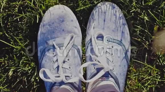 女足穿着运动鞋穿着蓝色牛仔裤穿着彩色运动鞋缓慢地在阳光下的绿草上移动和摆姿势视频的预览图