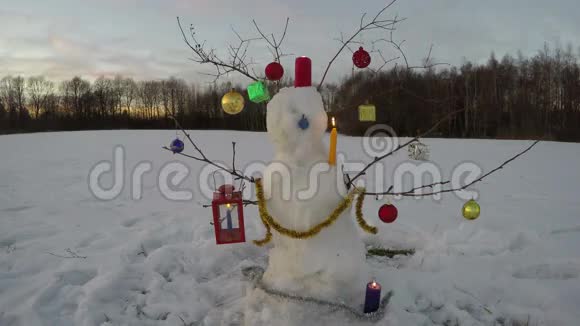 新年圣诞节期间雪人在田野上戴着蜡烛和晚霞视频的预览图